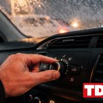 Mano girando el mando de velocidad del ventilador de la calefaccion en el salpicadero de un coche